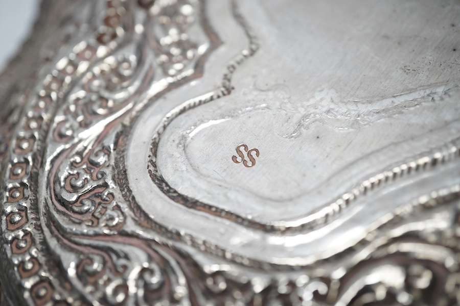 A Thai white metal cigarette box, wood lined, stamped Thainakon, 20cm and a Ceylonese white metal dish, shaped in the form of the country, with embossed borders, and inscription, maker’s mark SS, 24.7cm long, 182g. Condi